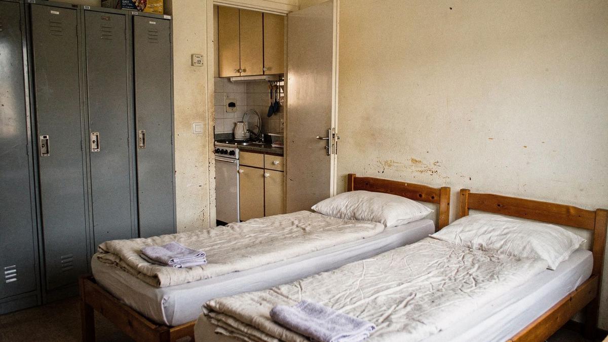 Shared apartment bedroom with twin beds, lockers and a full kitchen, set up for a festival group